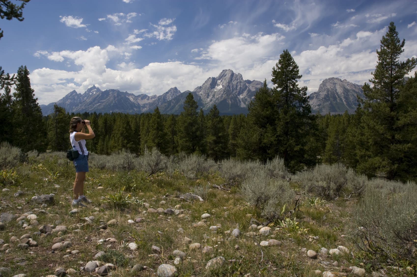 hiker looking at the tetons through binoculars